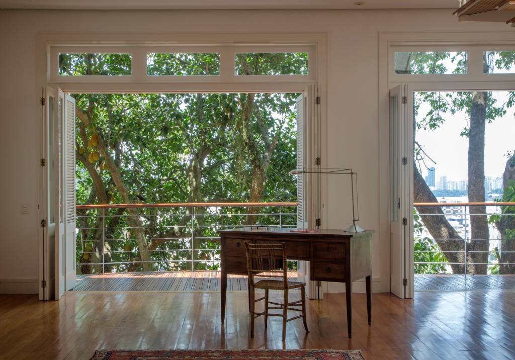 imagem mostra uma escrivaninha na sala com luz natural e janelas