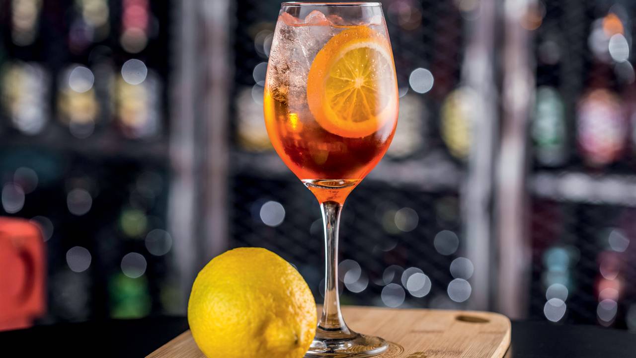 A imagem mostra uma taça com aperol spritz