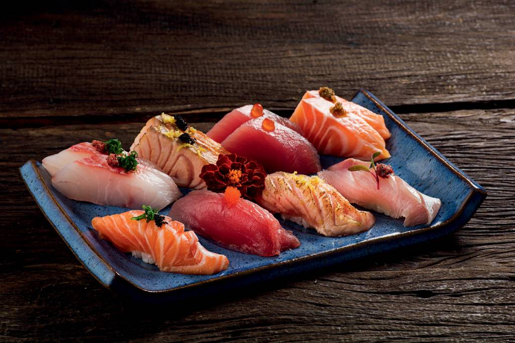 A imagem mostra uma louça com peças de sushi e sashimi