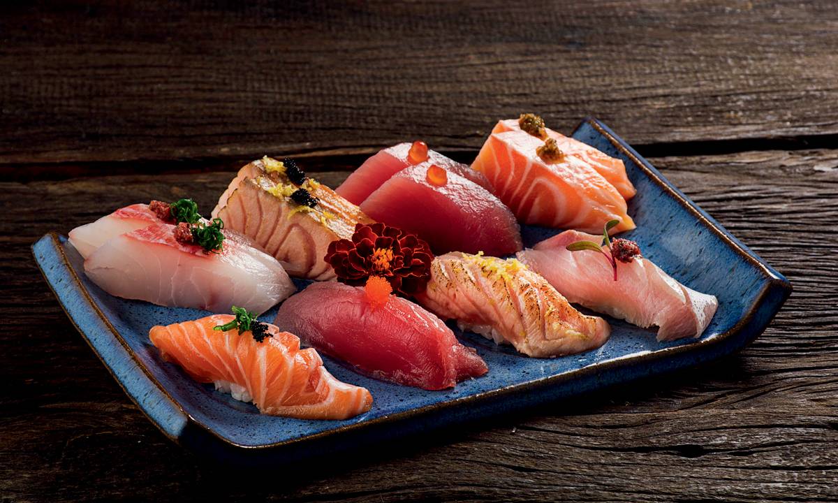 A imagem mostra uma louça com peças de sushi e sashimi
