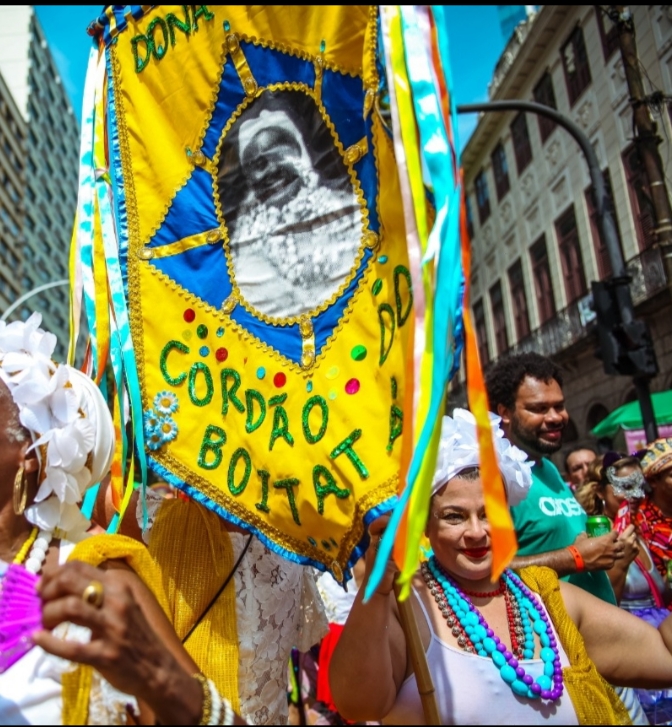 Bloco de Carnaval com estandarte amarelo do bloco Cordão do Boitatá em destaque