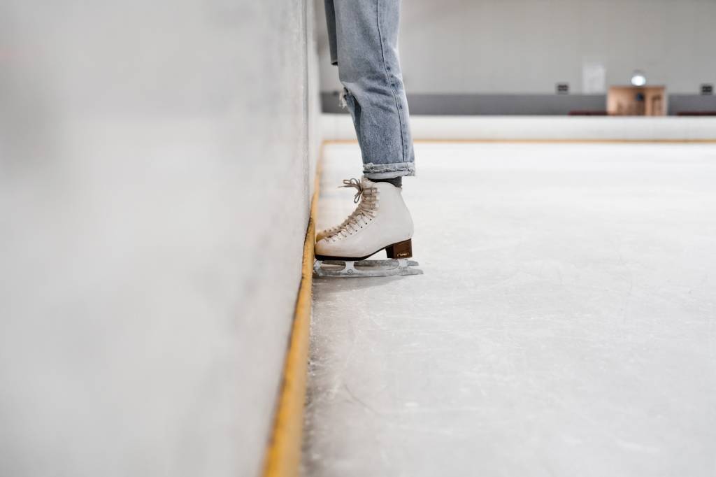patinação no gelo Pernas com patins numa pista de patinação no gelo