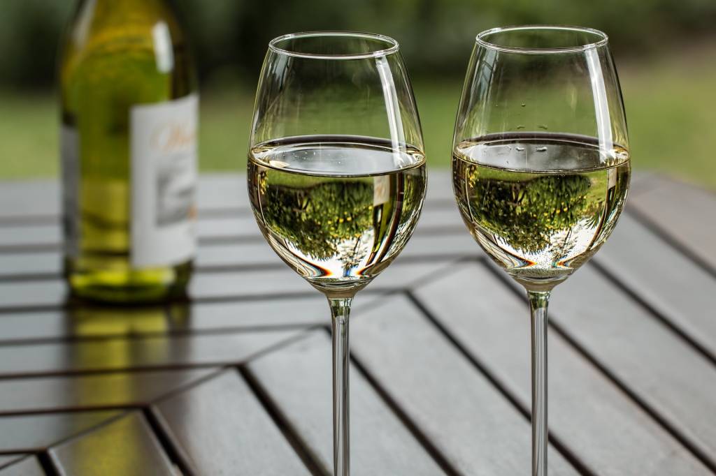 A imagem mostra duas taças de vinho branco