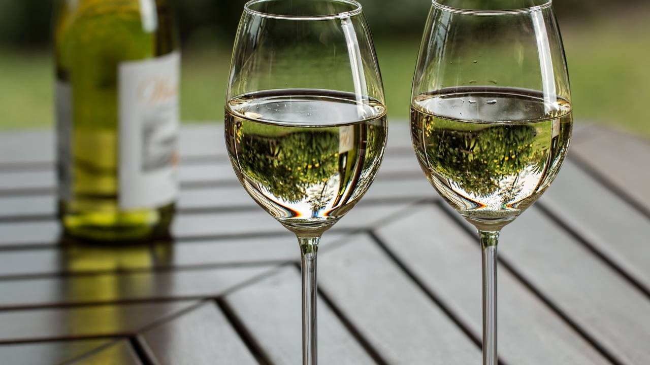 A imagem mostra duas taças de vinho branco