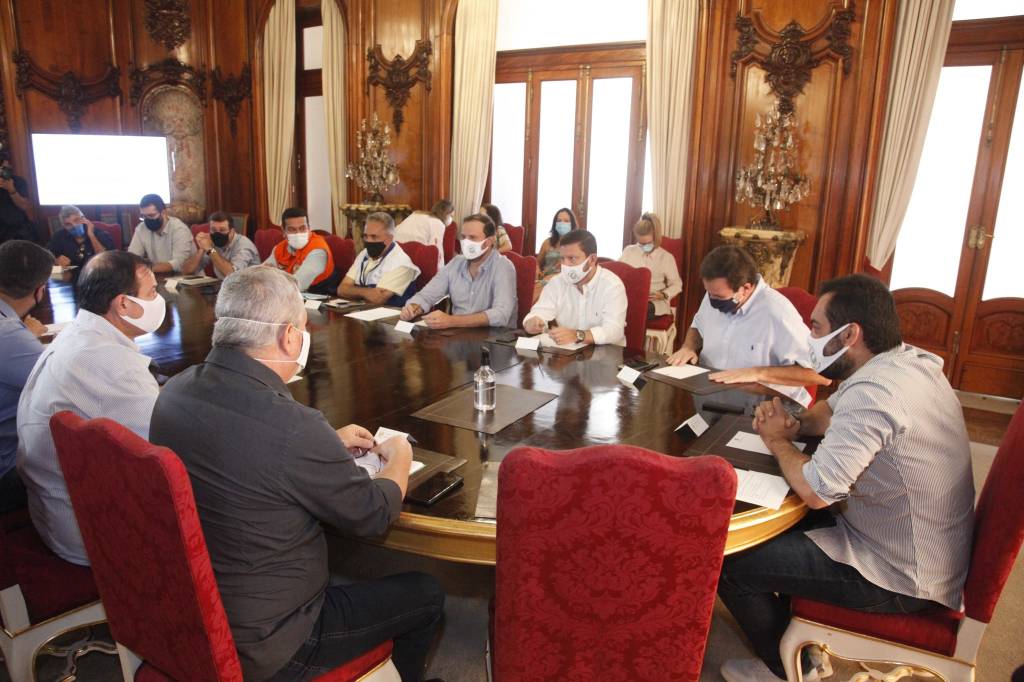 Prefeitos e governador estão sentados em uma mesa de reunião