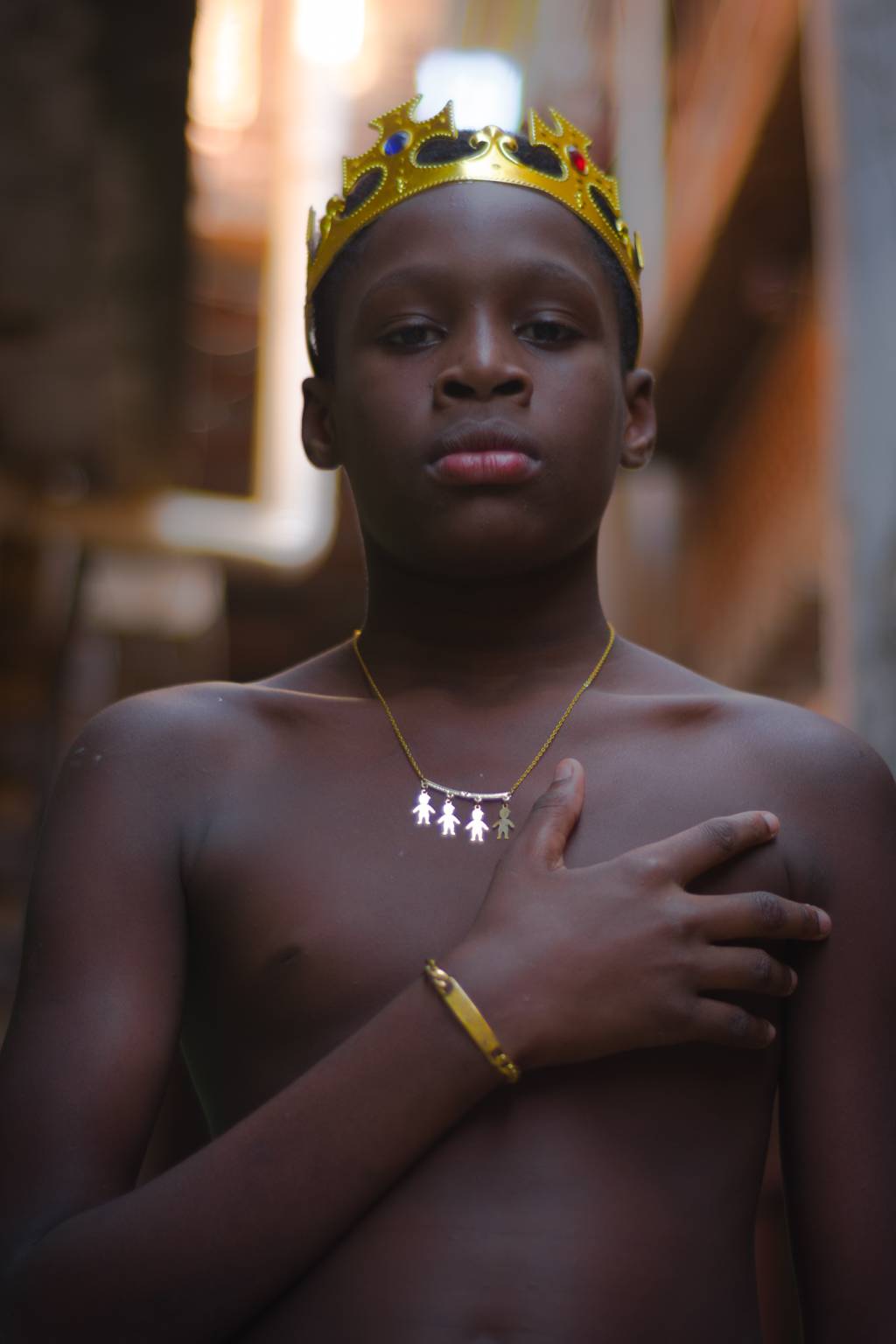 _ Menino negro com mão no peito e coroa dourada na cabeça