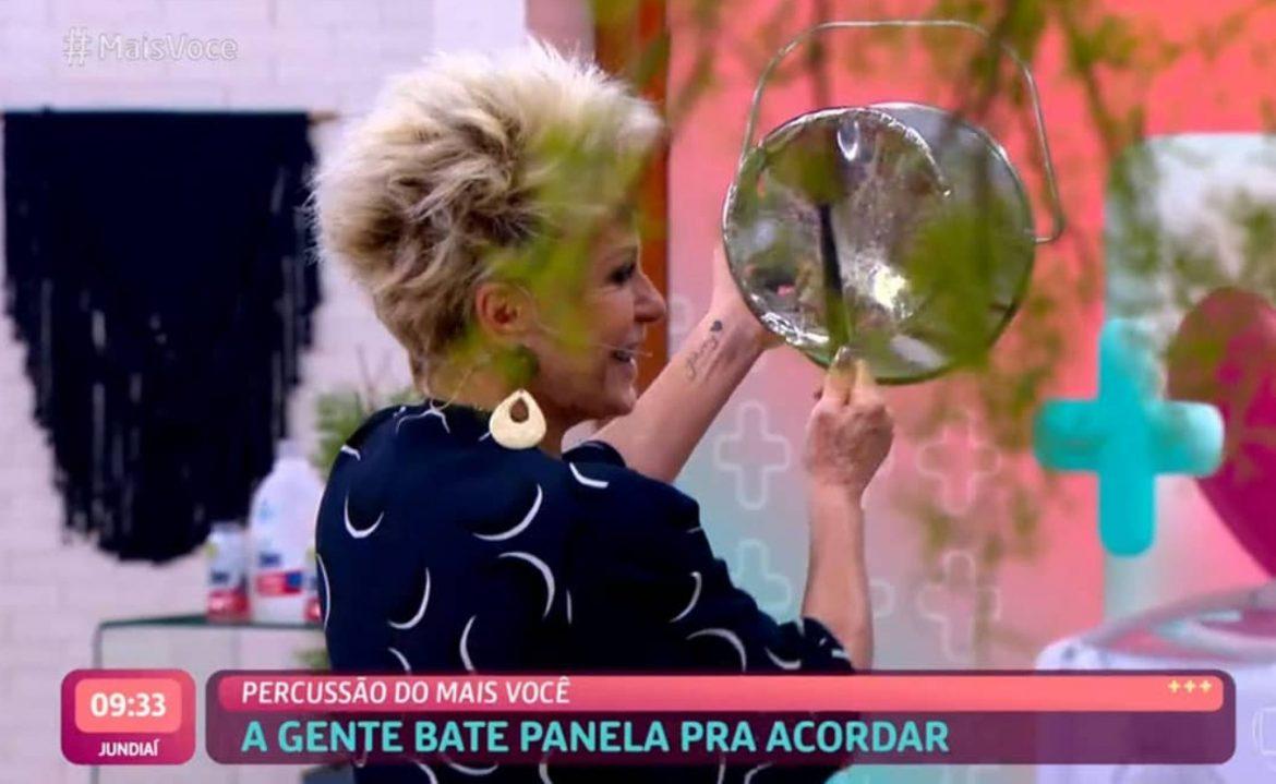 A imagem mostra Ana Maria Braga batendo numa panela com uma colher