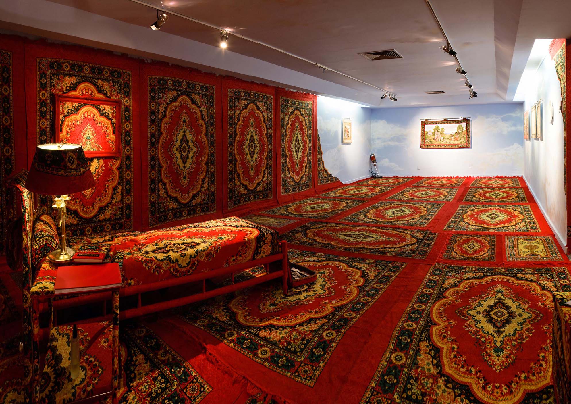 Sala da exposição na Casa França-Brasil com diversos tapetes persas pelas paredes e pelo chão