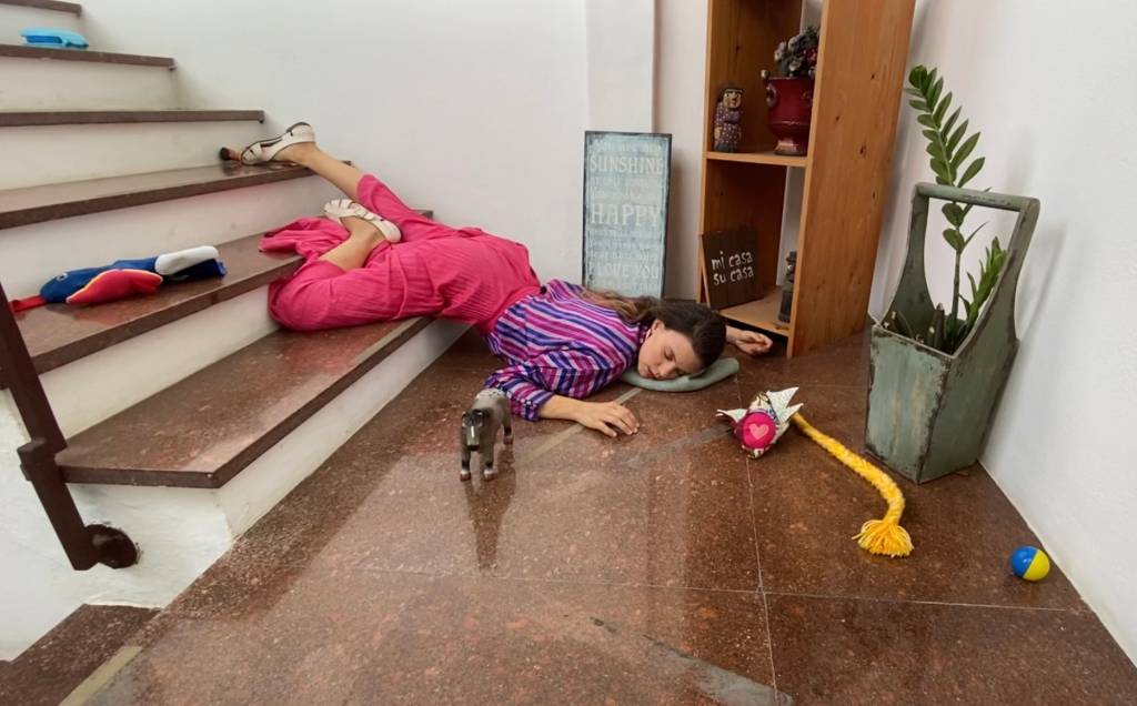 Joana Lerner caída numa escada, com brinquedos espalhados ao redor
