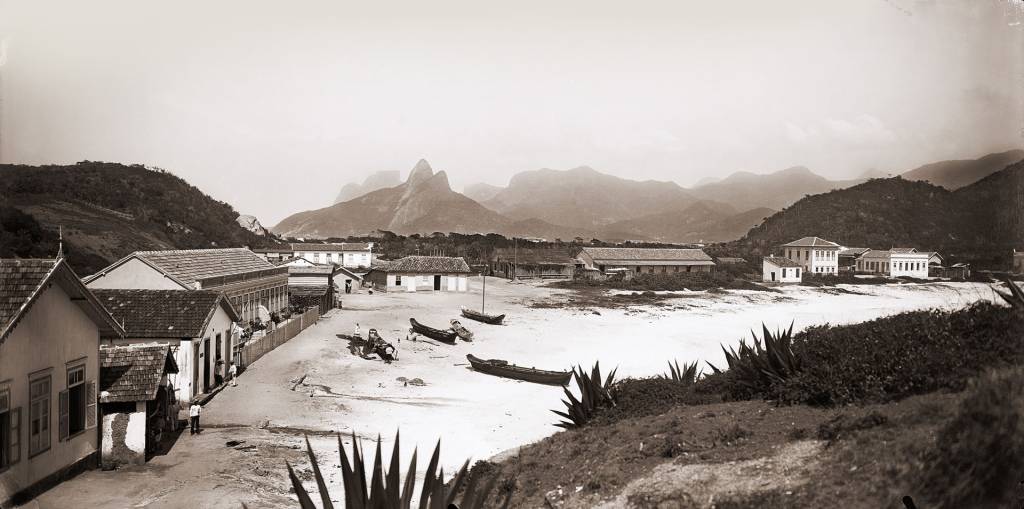 Imagem de 1895 mostra local onde hoje é o posto 6, em Copacabana. Há construções bem simples junto à areia e o Morro Dois Irmãos ao fundo