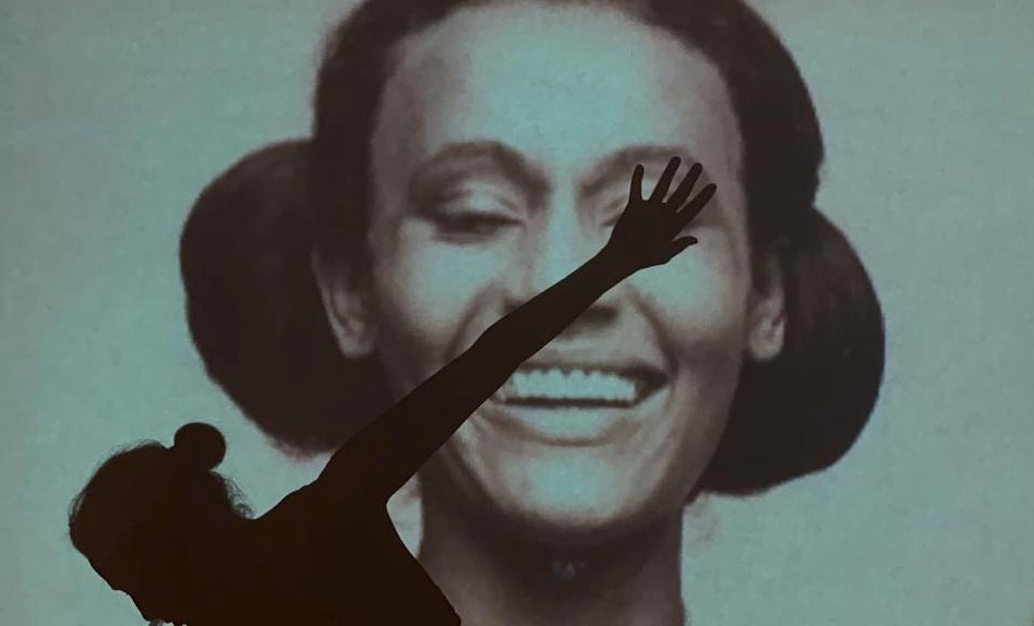 Matriaquia Camila Pitanga na frente de uma projeção na parede de foto da própria mãe