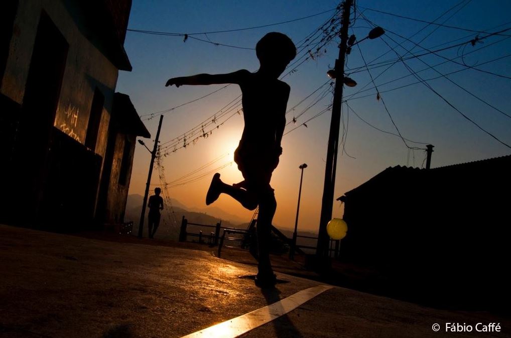 Criança jogando bola na fvela