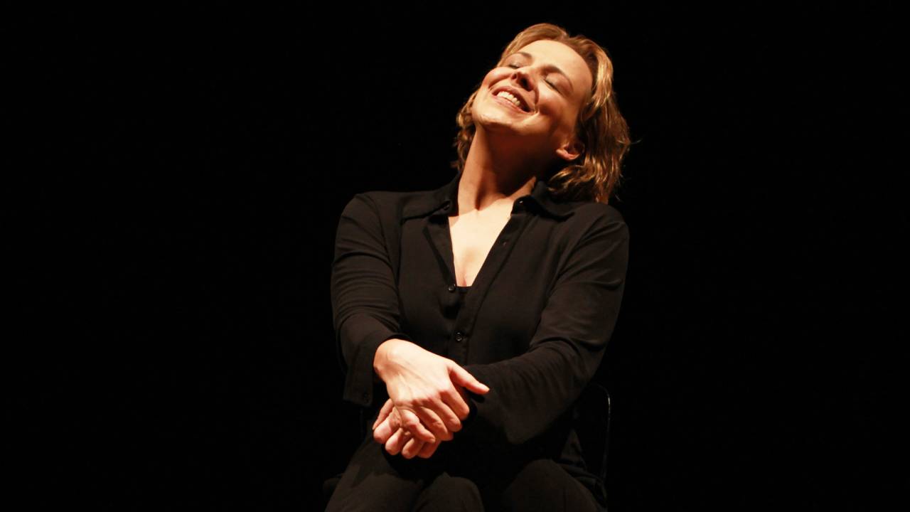 Ana Beatriz Nogueira sorrindo, com o rosto para cima, no palco
