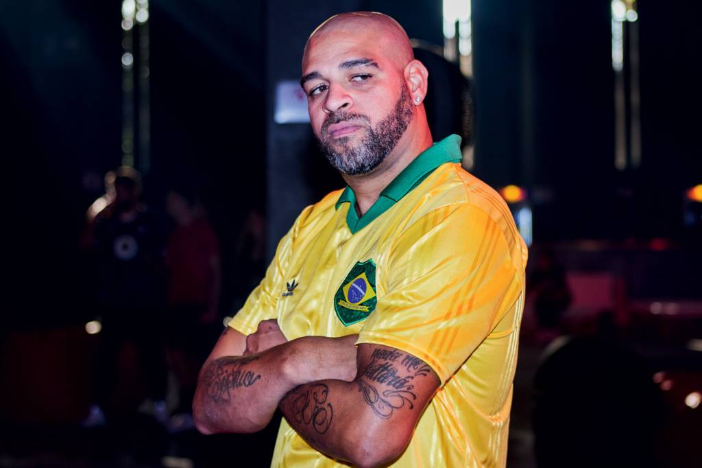 A imagem mostra jogador Adriano, de braços cruzados, vestindo uma camisa da seleção brasileira