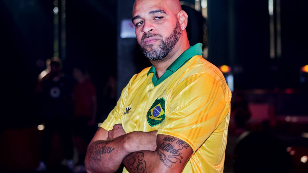 A imagem mostra jogador Adriano, de braços cruzados, vestindo uma camisa da seleção brasileira