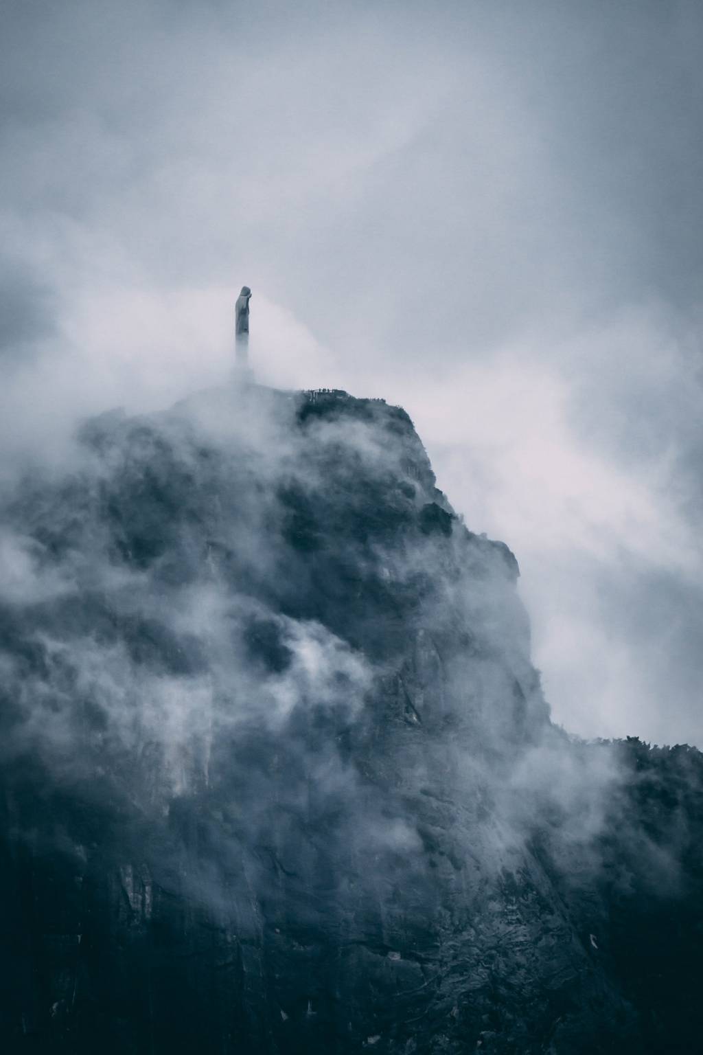 A imagem mostra o Cristo Redentor parcialmente coberto por nuvens