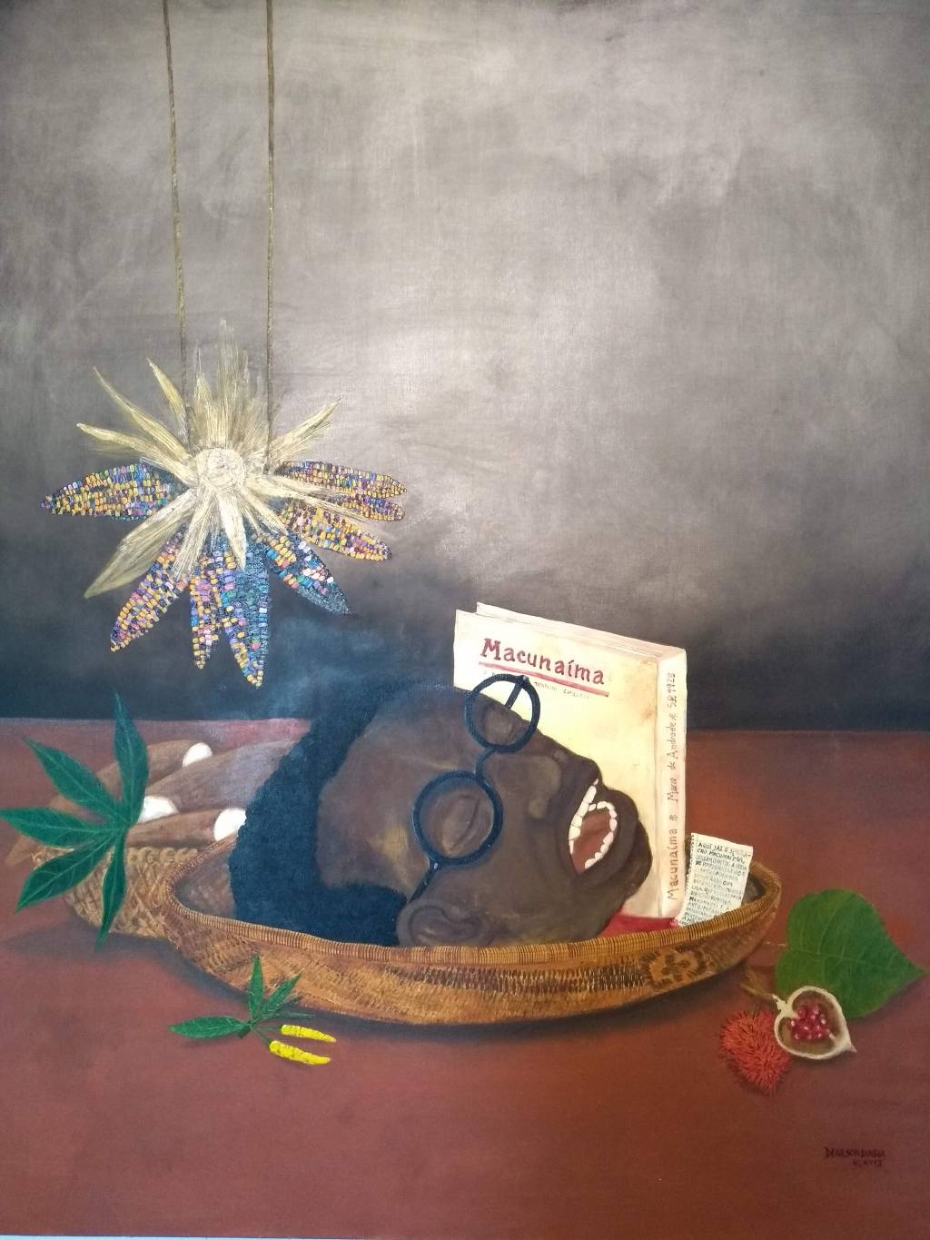 Pintura de Denilson Baniwa mostra cabeça de um homem negro de óculos sobre uma bandeja numa mesa, com algumas plantas ao lado