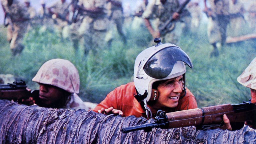 Roberto Carlos jovem, de capacete, abaixado numa trincheira