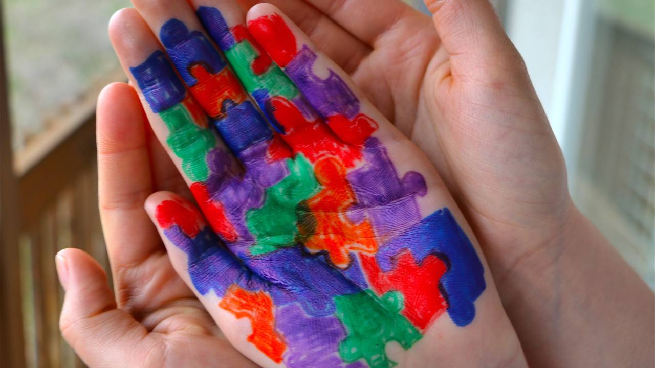 Símbolo da campanha do autismo pintado na mão de uma criança.