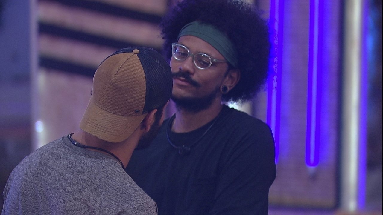 A imagem mostra os BBB João Luiz, de frente, e Rodolffo, de costas, de boné, no que parece ser uma discussão