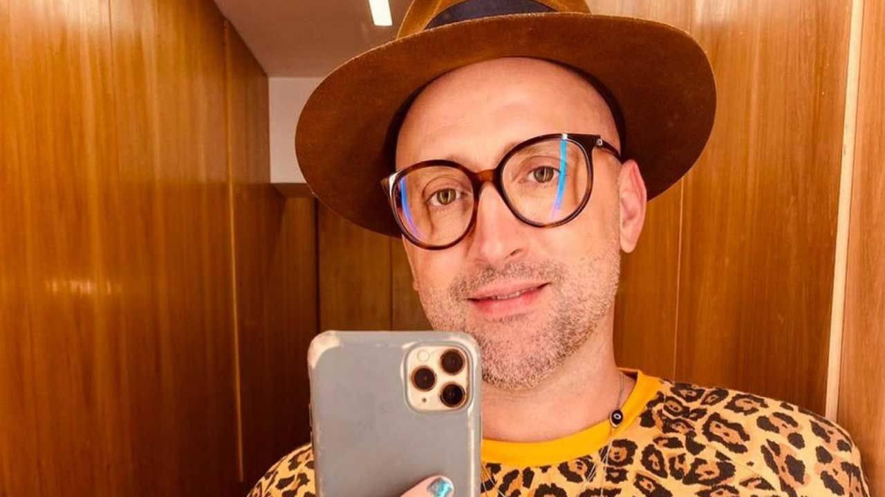 A imagem mostra o ator Paulo Gustavo, de óculos e chapéu fazendo uma selfie com o celular
