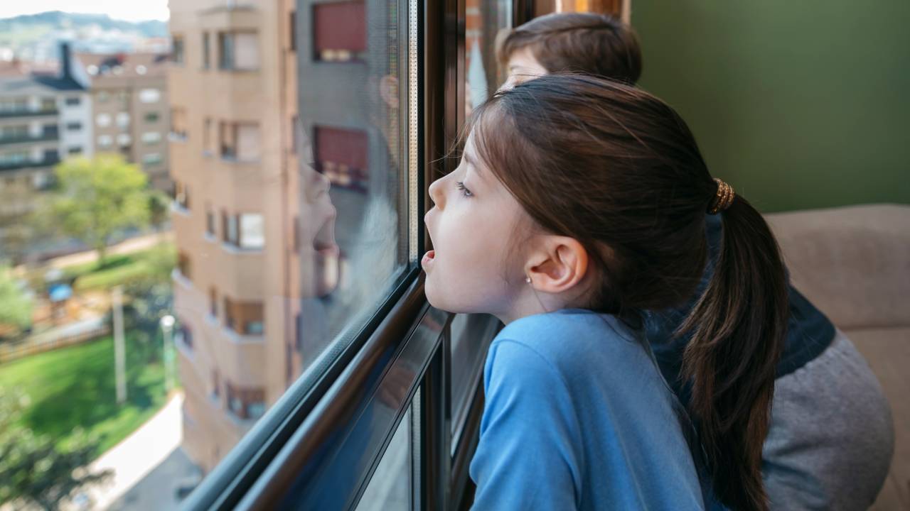 Crianças em isolamento veem a vista de uma janela.