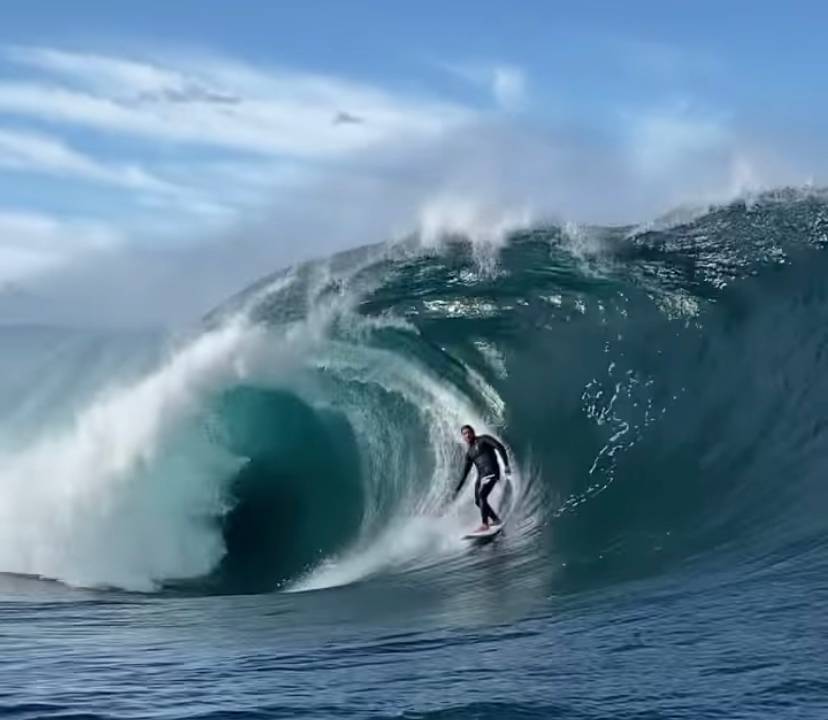 A imagem mostra o surfista Caio Vaz numa onda grande e tubular