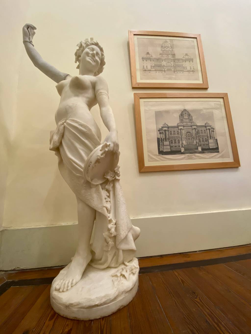 Estátua de mulher com um pandeiro na mão, em mármore