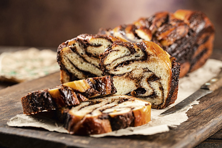 A imagem mostra um pão babka com nutella e chocolate em parte fatiado da L’Ufficio Di Luca