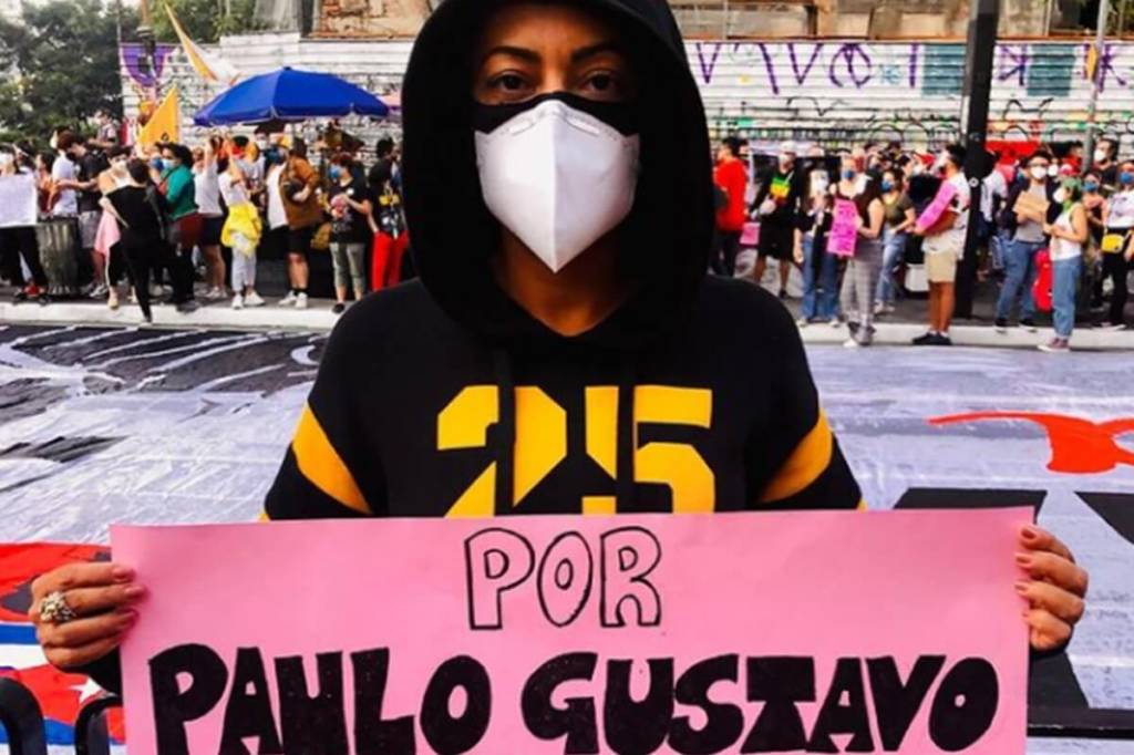 A imagem mostra a atriz Samantha Schmütz segurando um cartaz com o nome de Paulo Gustavo, no meio da manifestação, em São Paulo