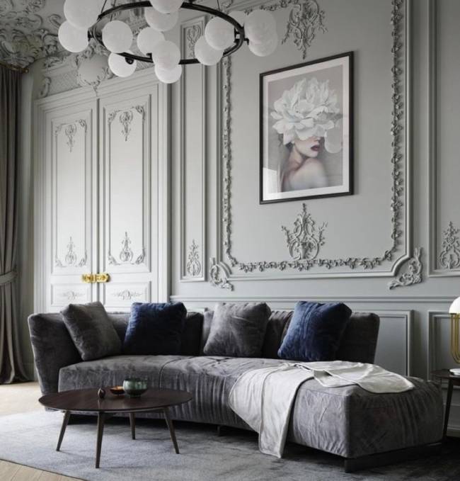 Boiserie clássica A imagem mostra uma sala de estar com boiserie. Em segundo plano um sofá com almofadas e um lustre no teto.