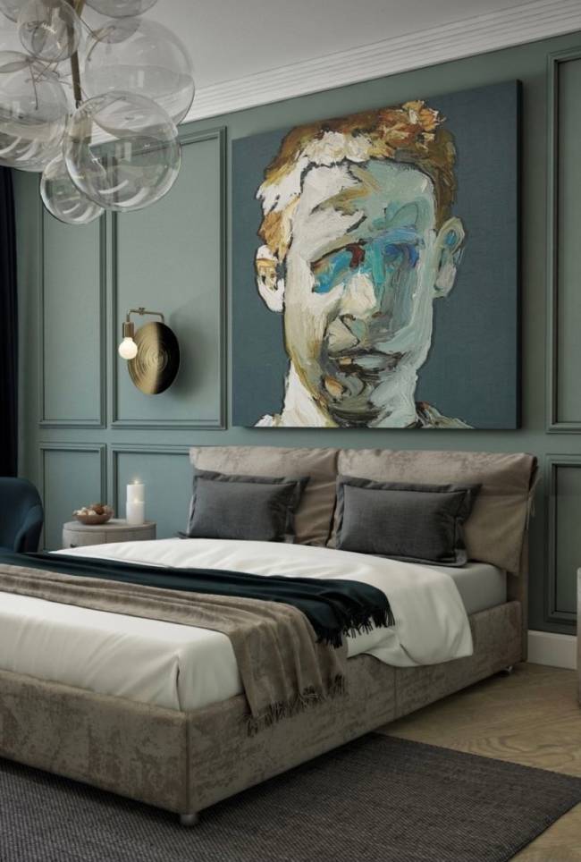 Boiserie A imagem mostra em primeiro plano uma parede com boiserie e um quadro. Em segundo plano uma cama com um lustre no teto.