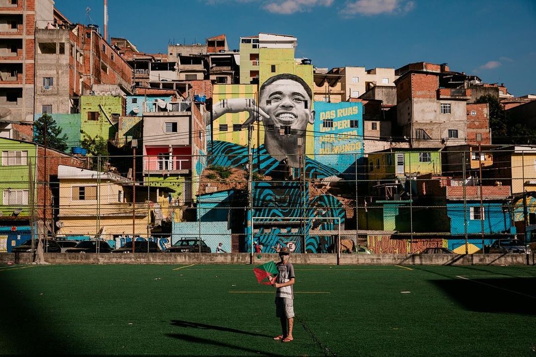 Uma criança segura uma pipa na mão em um campo de futebol na favela do Jardim Peri, que fica ao lado da favela do Peri Alto.