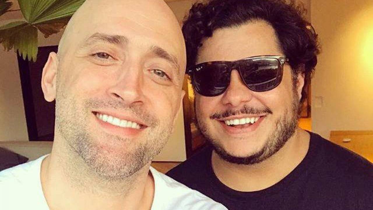 A imagem mostra os atores Paulo Gustavo e Marcus Majella, de óculos escuros, sorrindo