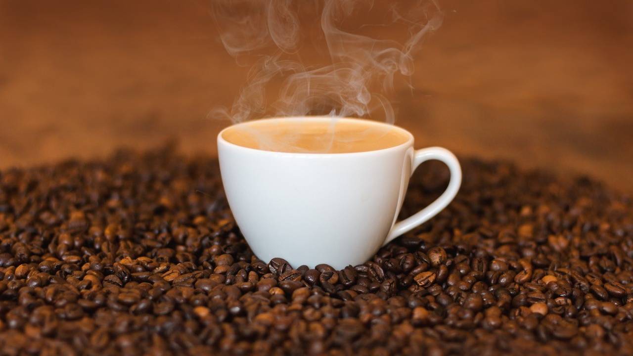 A imagem mostra uma xícara de café sobre grãos moídos