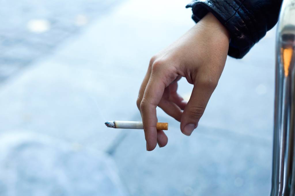 Mão feminina segurando cigarro