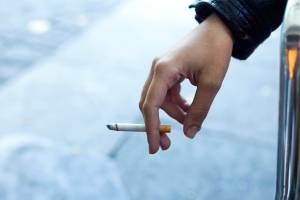 Womans hand with cigarette in the street.