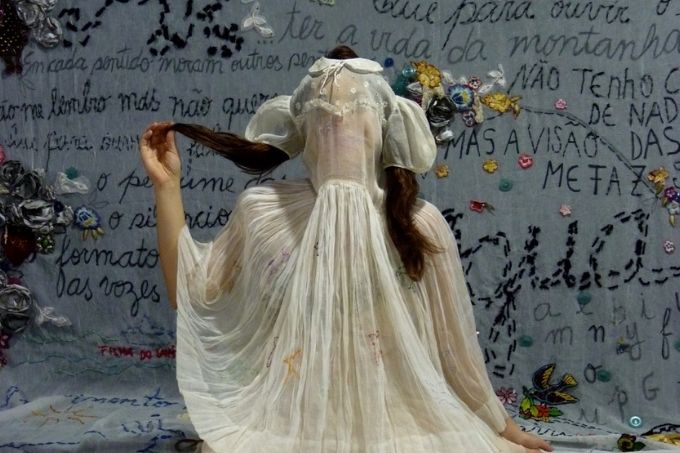 Sara Antunes num cenário todo bordado com um vestido e um véu sobre a cabeça