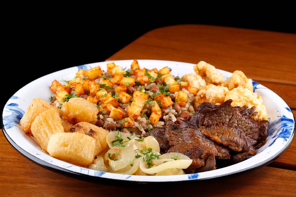 A imagem mostra um prato com baião de dois e carne
