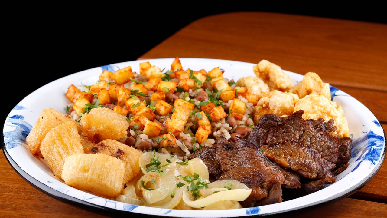 A imagem mostra um prato com baião de dois e carne