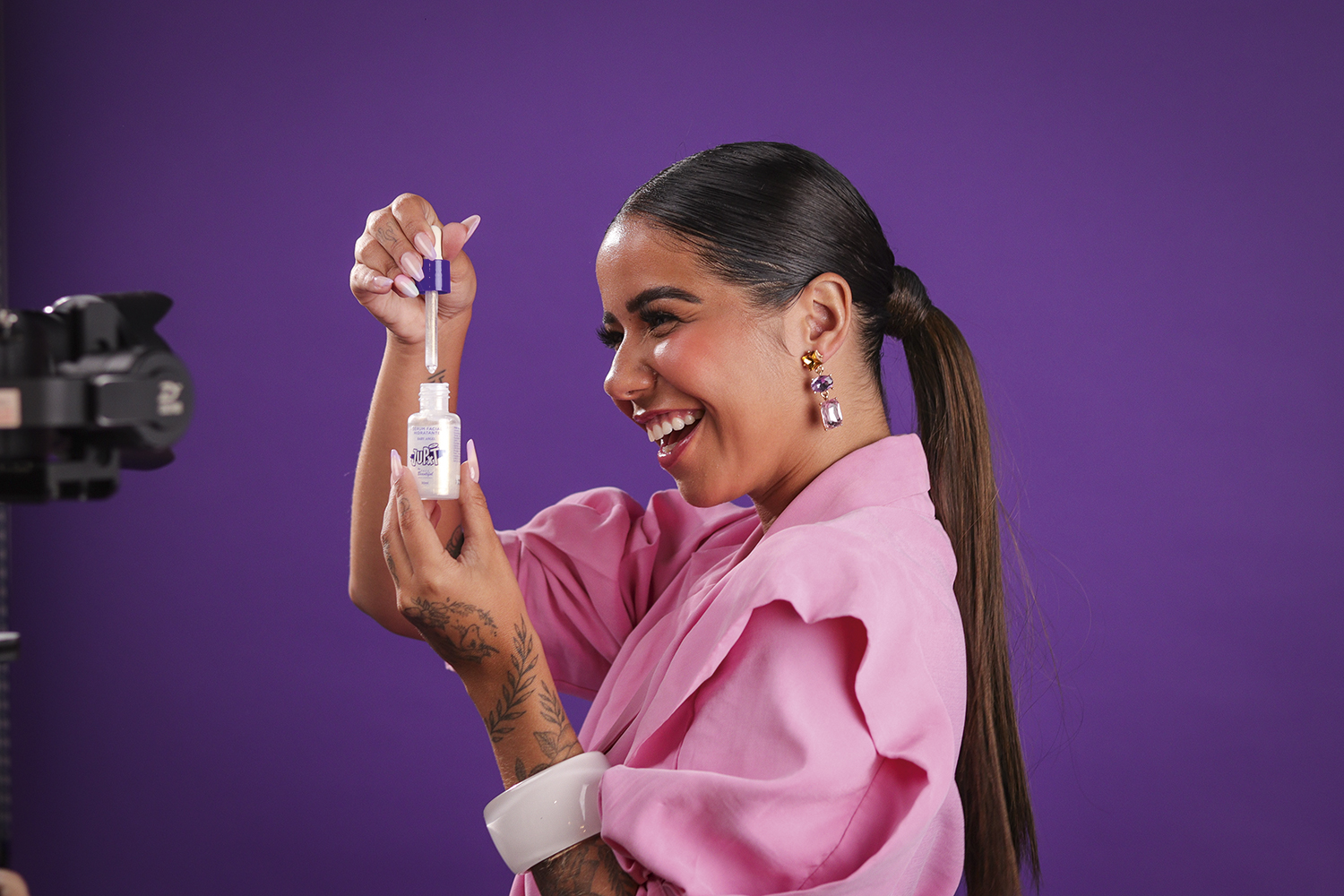 Júlia Peixoto de lado, segurando um frasco de maquiagem