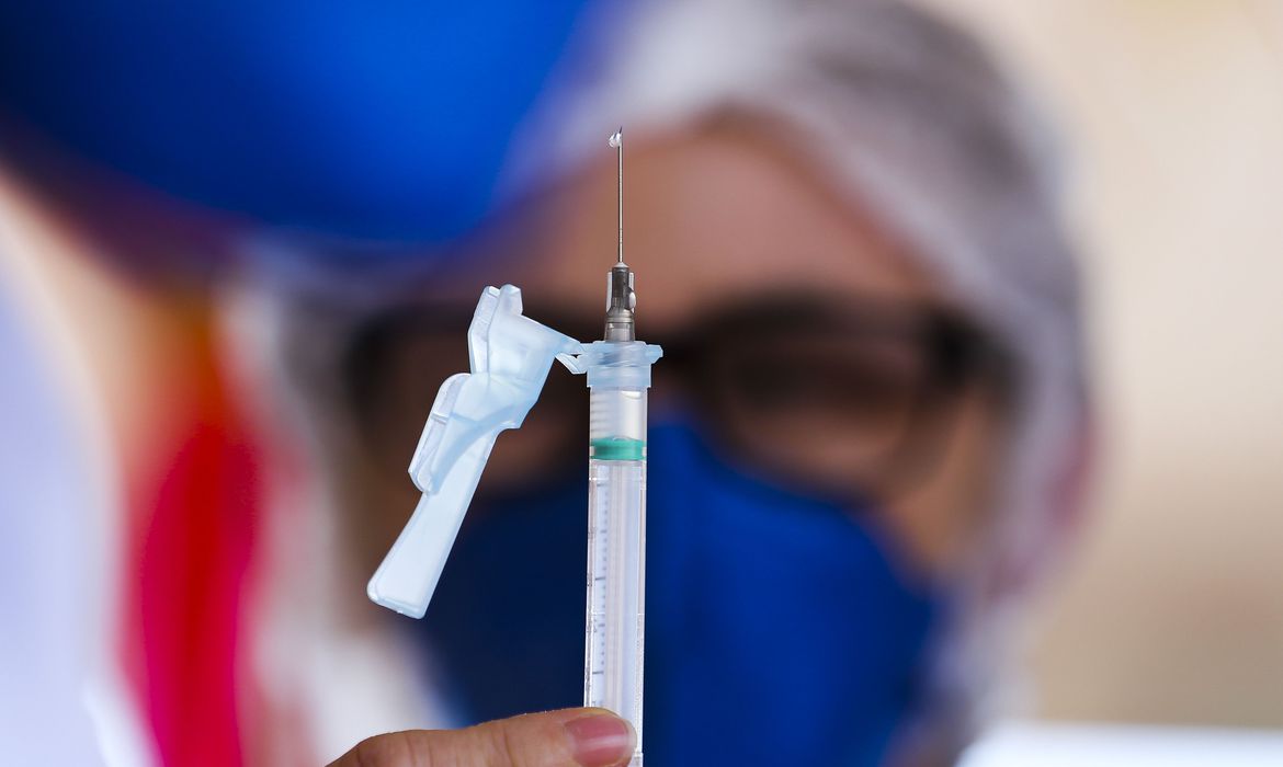 Profissional da saúde segura seringa para aplicação da vacina