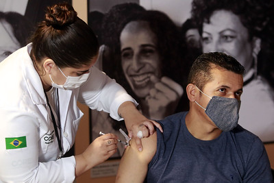 Homem recebe vacina contra a Covid-19 aplicada por mulher profissional da saúde