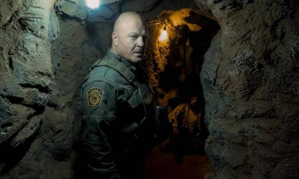 Agente policial está em uma caverna com pouca iluminação