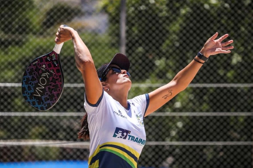 Foto mostra jogadora praticando tênis na praia