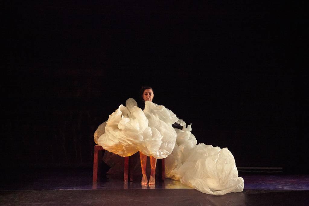 Atriz no palco com um grande tecido em volta dela