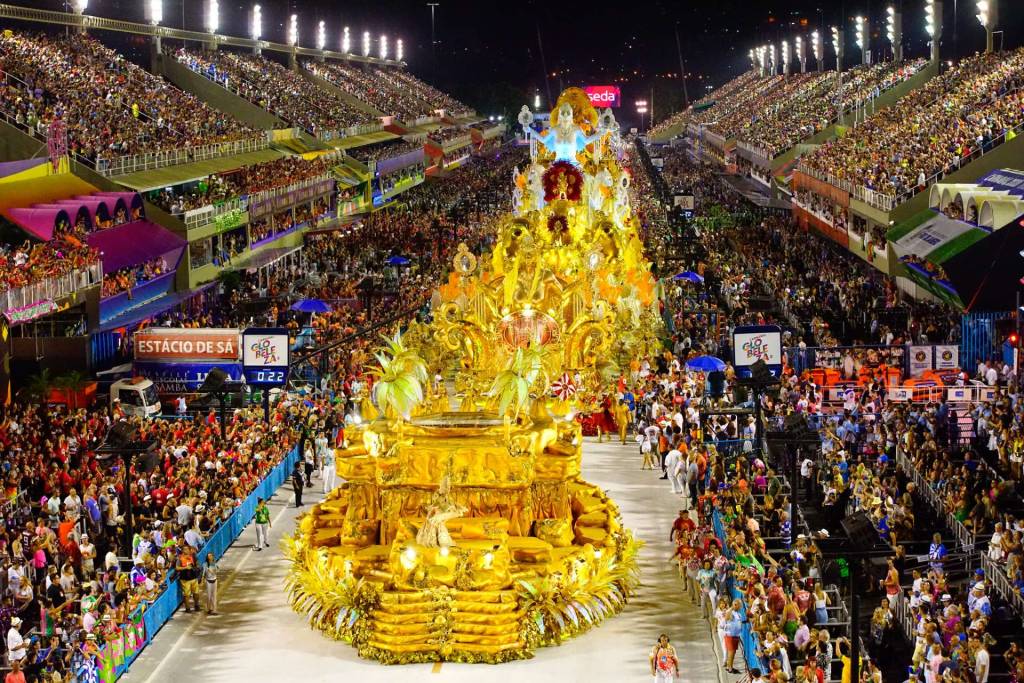 A imagem mostra o desfile de uma escola de samba na Sapucaí, vista do alto