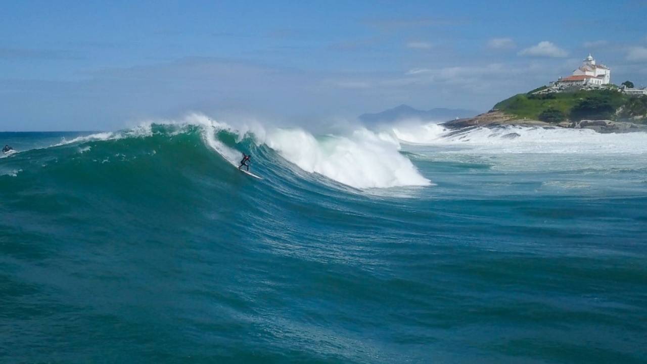 Foto mostra pessoa surfando em uma onda em Saquarema