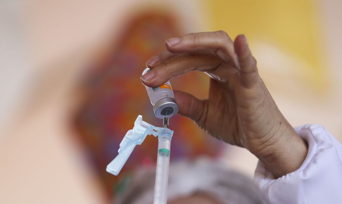 Foto mostra frasco com a vacina contra a Covid-19 sendo injetado