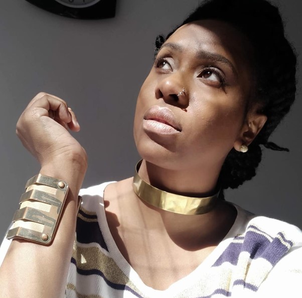 Caroline Amanda – divulgação Foto mostra uma mulher negra com o rosto voltado para o sol, usando joias douradas